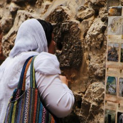 Vrouw kust de muur bij de Via Dolorosa