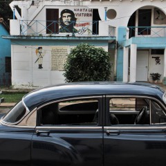 Een oude Amerikaanse auto naast een muurschildering van Che in Viñales.